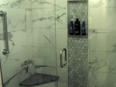 A master bathroom remodel featuring a shower with vertical marble accent tile, niche, and seat on Anna Maria Island, Florida